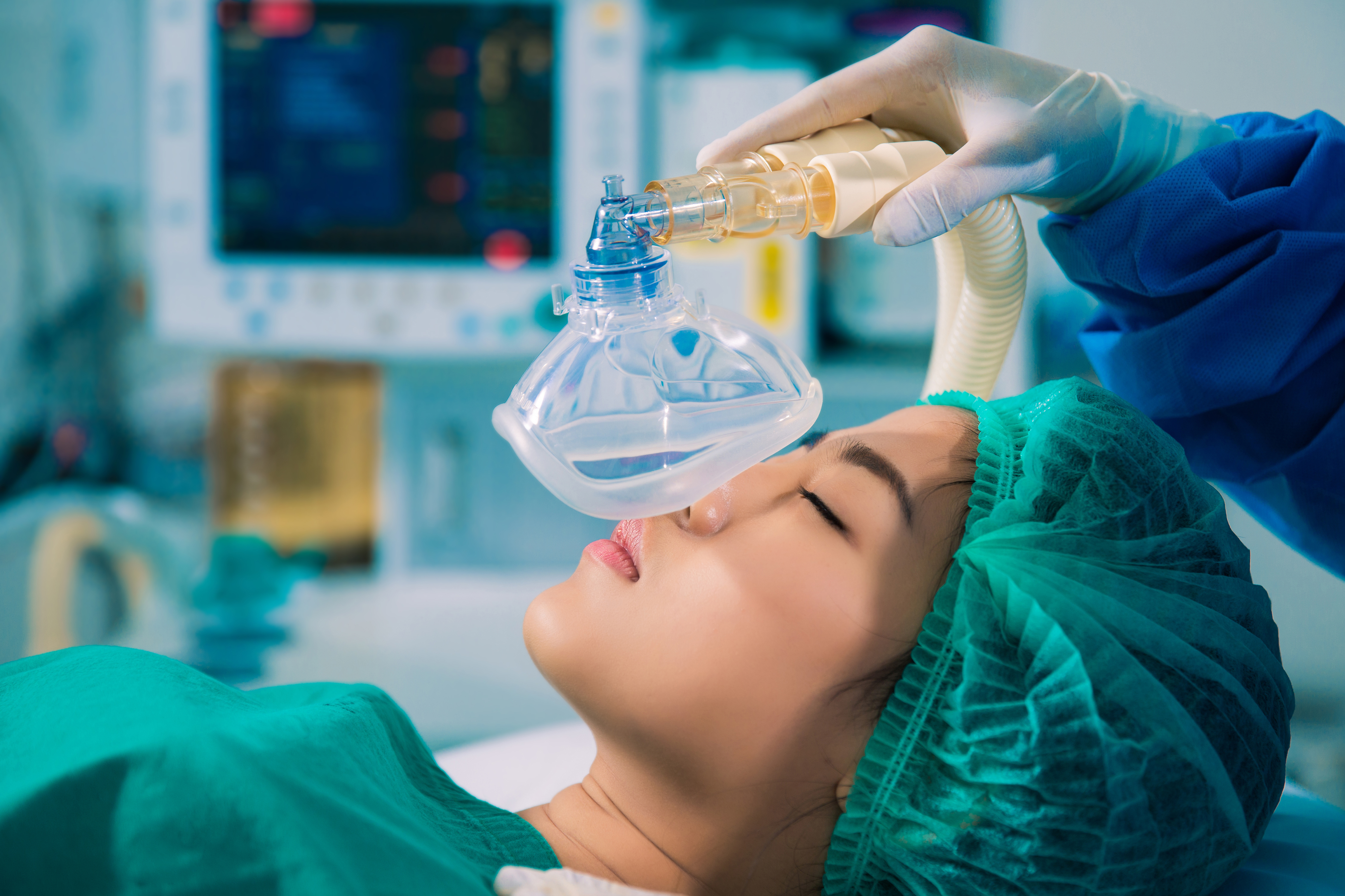 A woman on an operating table with a medical mask held over her face